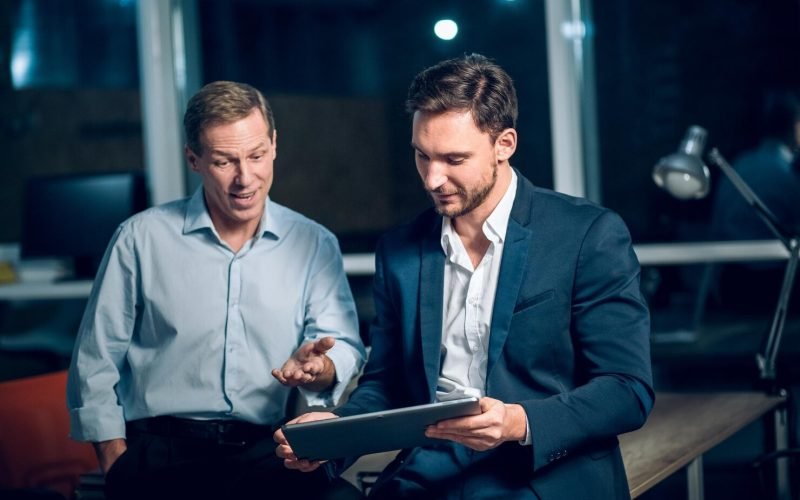 two-office-workers-with-tablet-office-late-night-young-businessmen-talking-while-viewing-presentation-digital-touchscreen-tablet_549566-692
